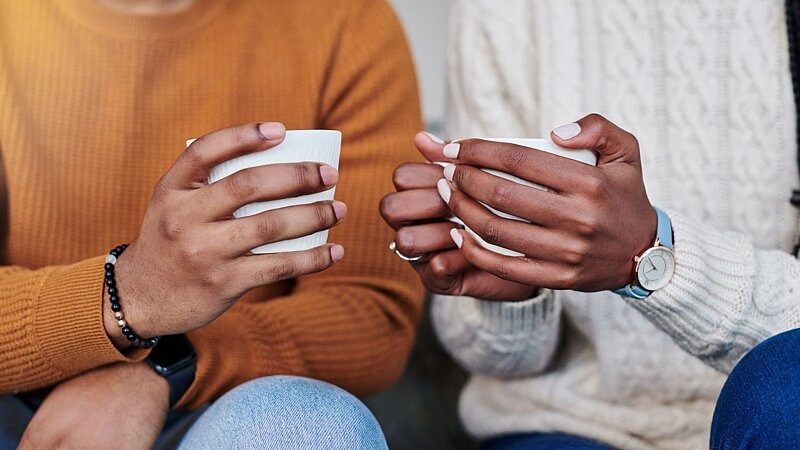 Zwei Personen sitzen nebeneinander und halten jeweils eine Tasse in den Händen – eine ruhige Gesprächssituation, die Offenheit und Austausch zwischen Angehörigen und Betroffenen symbolisiert., Bild: jeffbergen / gettyimages